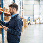 Inventario almacén: cómo hacerlo paso a paso Profesional escaneando productos durante un inventario en un almacén industrial organizado